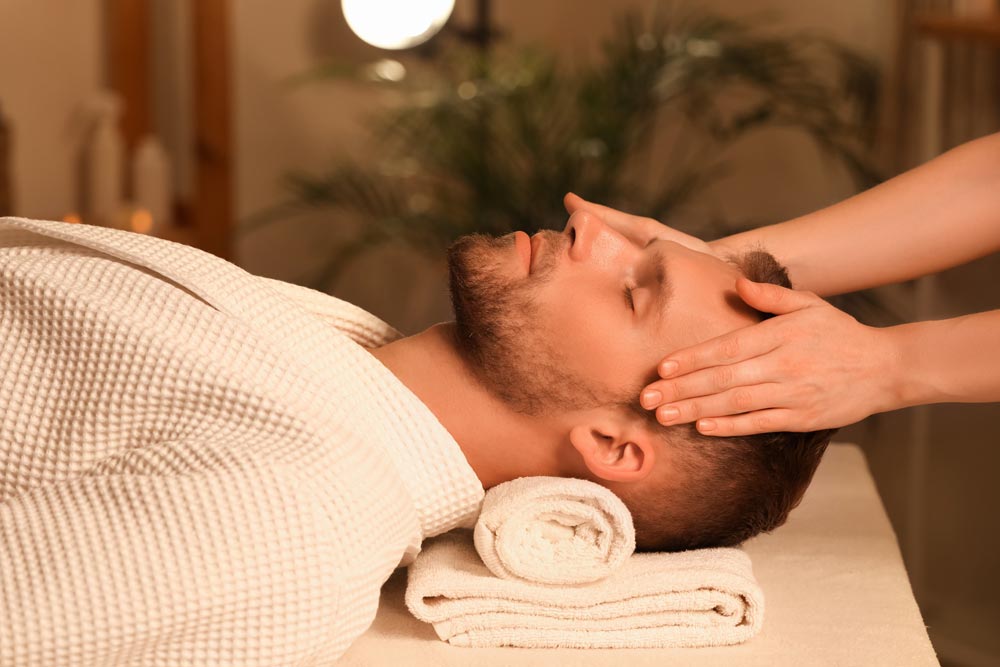 Spa professional giving a male client a facial massage, highlighting men’s grooming and self-care trends
