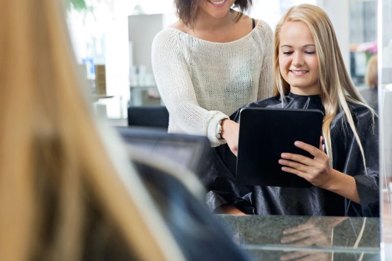 Hair stylist using a tablet during a client consultation in a professional salon